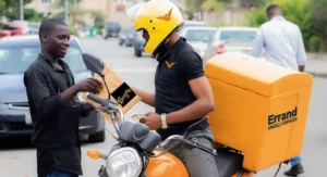 A delivery agent on a motorbike in Lagos traffic, carrying a branded delivery box labeled “Errand Angels Nigeria.